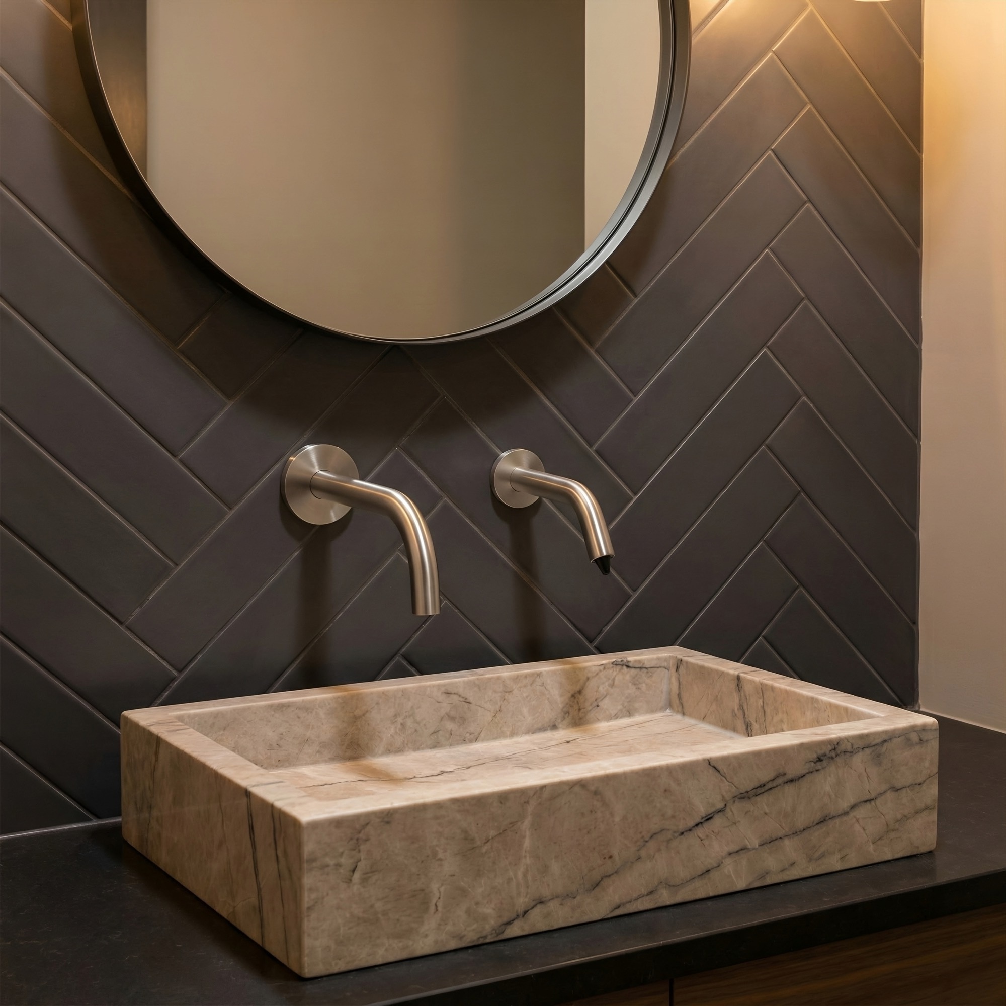 Wall-mounted metallic fixture pair above a stone basin.