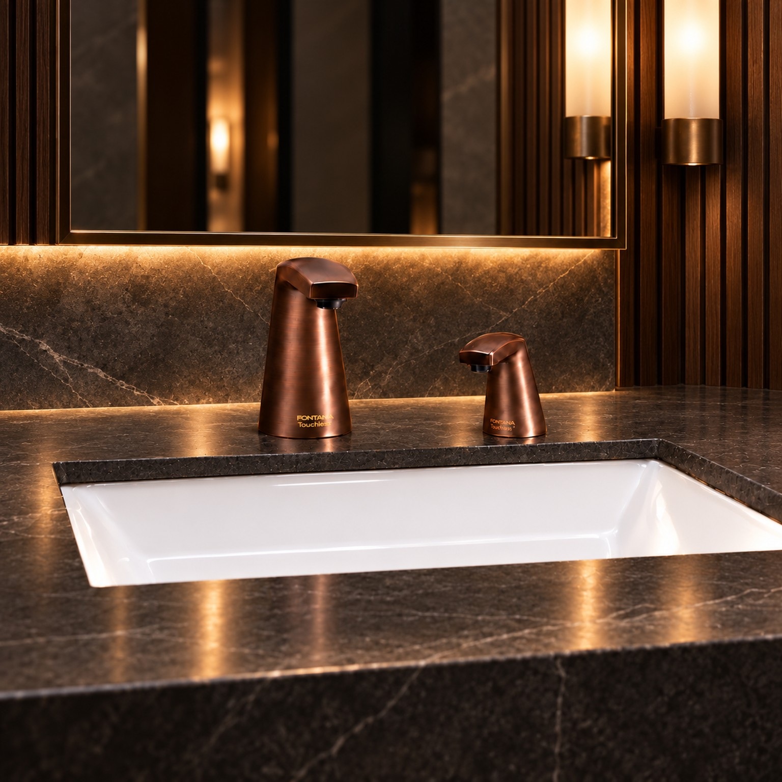 Copper-toned faucet and dispenser pair at a dark stone hospitality vanity.